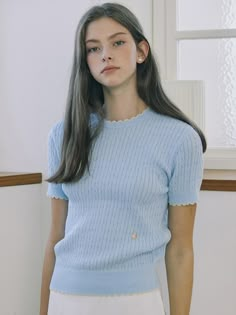 This product is a finely knit, cable-stitched top that combines the classic charm of a sweater with the ease of a t-shirt. It features a delicate contrast trim along the edges, adding a subtle pop of color to the otherwise understated design. The piece is finished with a ribbed hem and cuffs, which contribute to a snug and comfortable fit. - This top's crew neck design offers a timeless look that pairs well with various jewelry and necklines.- The cable knit pattern is meticulously crafted, adding texture and visual interest to the garment.- Its short sleeves make it suitable for warmer days or can be layered during cooler seasons.- A pair of small, decorative buttons at the hem introduces an element of sophistication to the overall design. Classic Blue Textured Knit Top, Light Blue Ribbed Knit Top, Classic Blue Knit Tops, Blue Textured Knit Crew Neck Top, Light Blue Knitted Top For Spring, Spring Light Blue Knitted Tops, Light Blue Textured Knit Top, Light Blue Knitted Crew Neck Top, Solid Color Pointelle Knit Crew Neck Tops