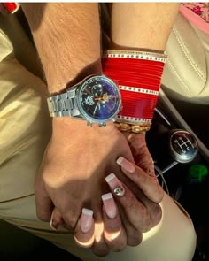 two people holding hands while sitting in a car with one woman's hand on the steering wheel