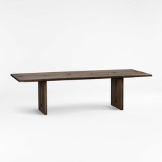 a long wooden table sitting on top of a white floor next to a gray wall