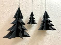 three black paper christmas trees hanging from strings