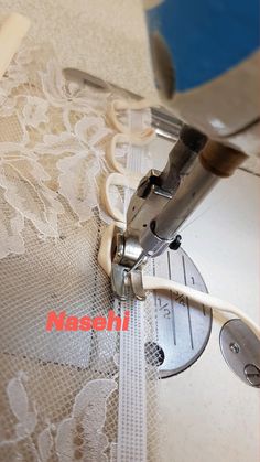 the sewing machine is working on the white lace fabric that has been sewn together