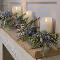 some candles are sitting on a table with greenery