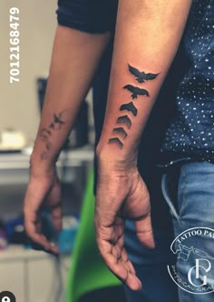 two people holding hands with tattoos on their arms and one has a bird in the middle