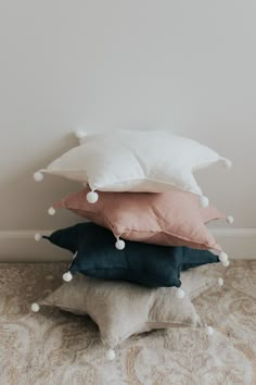 four pillows stacked on top of each other with pom - poms around them