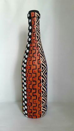 an orange and black vase sitting on top of a white table next to a wall