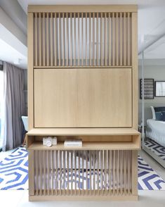 a bed room with a neatly made bed next to a wooden shelf on the floor