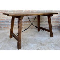 a wooden table sitting in front of a brick wall with a hose connected to it