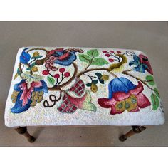 an embroidered foot stool with flowers and leaves on it