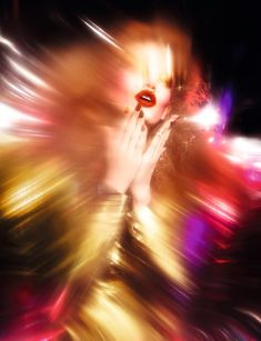 a woman with her hands on her face in front of blurry lights and colors