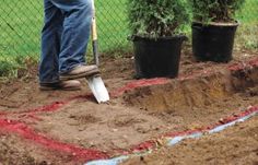 a man is shoveling dirt in front of some potted plants on the ground