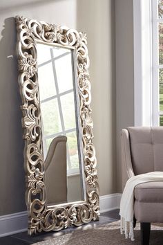 a large mirror sitting on top of a floor next to a chair in a living room