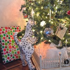 a christmas tree with presents under it and a cat statue next to it, all wrapped in wrapping paper