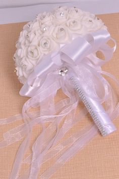 a bridal bouquet with white roses and crystal brooches on the top is sitting on a table