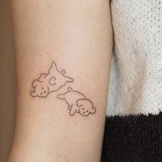 a small tattoo on the arm of a woman's left arm with two dogs