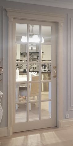 an open door leading to a kitchen and dining room with white furniture in the background