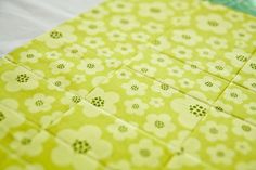 a close up view of a yellow and white quilt with flower designs on the edges