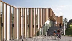 people are walking up and down the stairs in front of a building with wooden slats