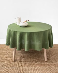 a table with a green cloth on it and a white bowl sitting on top of it