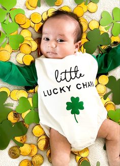 a baby laying on the ground wearing a st patrick's day bib that says little lucky charm