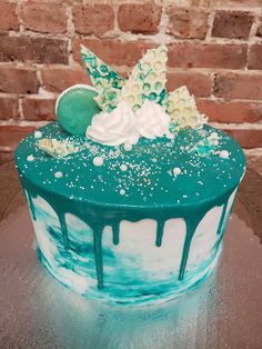 a cake with blue and white icing on it sitting on a table next to a brick wall