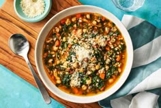 a bowl of soup with spinach, carrots and parmesan cheese