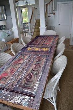 an old wooden table is in the middle of a room with wicker chairs around it