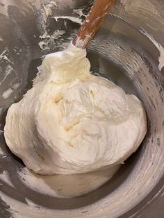 a mixing bowl filled with whipped cream and a wooden spoon in the middle of it