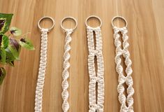 three crocheted scissors are sitting next to each other on a wooden surface with a plant in the background