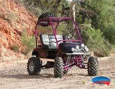 a pink and black buggy parked in the dirt