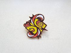 a yellow and red butterfly pin sitting on top of a white surface