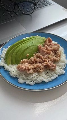 a blue plate topped with rice and meat next to a laptop