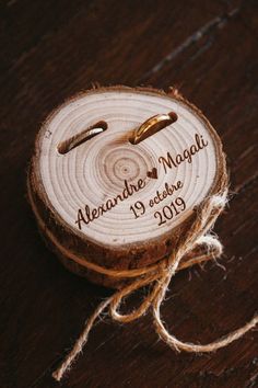 the wedding rings are on top of a wooden slice that has been tied to it