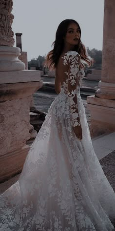 a woman in a white wedding dress standing on the street with her back to the camera