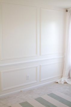 an empty room with white walls and striped carpet