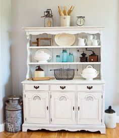 a white china cabinet with dishes on top