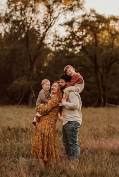 a family is posing for a photo in the field with their toddler son and mom