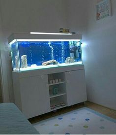 a fish tank sitting on top of a white cabinet next to a bed in a room