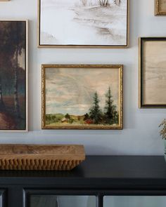 several paintings on the wall above a dresser