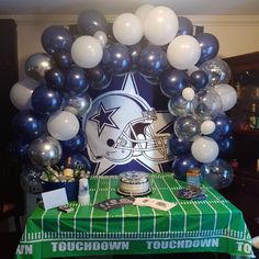 a table topped with balloons and football themed decorations on top of a green table cloth