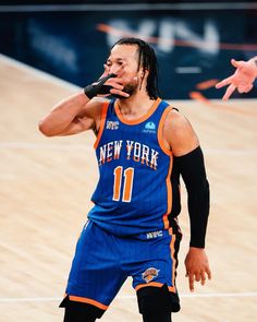 a basketball player with dreadlocks on his face and hands in the air while standing next to him