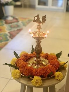 a small metal candle holder with flowers and candles in it on a table next to a tiled floor