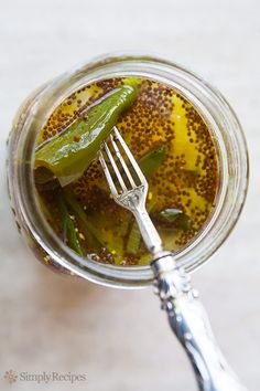 a glass jar filled with pickles and mustard