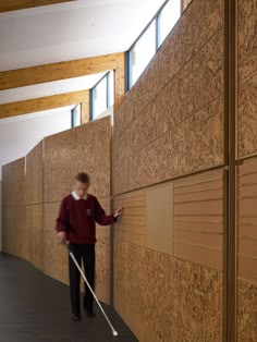 a person with a mop leaning against a wall and looking at something on the floor