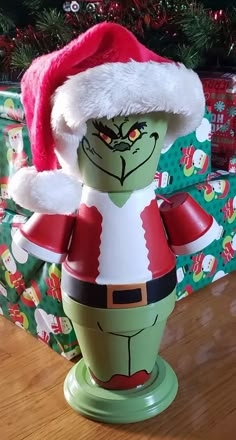 the grin face is wearing a santa hat and standing on a green pedestal with presents in the background