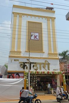 a building with a sign that says k on it and people riding motorcycles in front