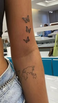 a woman's arm with butterflies and a world map tattoo on the left side