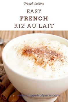 a white bowl filled with cream and cinnamon on top of a wooden table next to cinnamon sticks