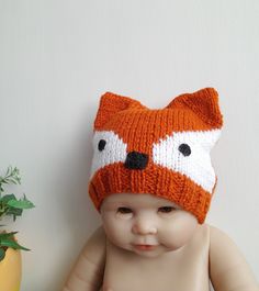 a baby wearing an orange knitted fox hat