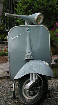 an old scooter is parked on the gravel