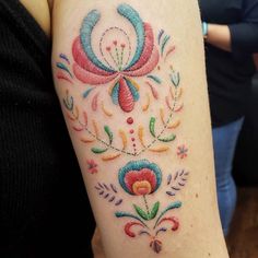 a woman's arm with colorful tattoos on it